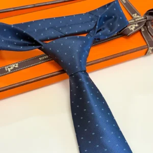 Hermès silk tie dark blue patterned fine ribbed texture luxury accessory displayed on orange box