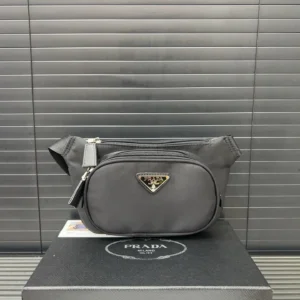 Prada Nylon Waist Bag in black, featuring a triangular logo, displayed on a black box with a textured background.