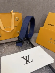 LV Shadow belt in blue leather with Monogram design, displayed alongside Louis Vuitton shopping bag and branded envelopes, emphasizing luxury accessory appeal.