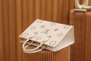 On The Go MM Monogram Empreinte 2-way tote bag by Louis Vuitton, featuring iconic monogram pattern and elegant design, displayed against a textured backdrop.
