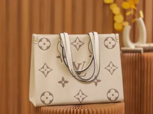 On The Go MM Monogram Empreinte 2-way Tote Bag by Louis Vuitton, featuring iconic monogram design, calf leather material, and stylish handles, set against a warm, textured background.