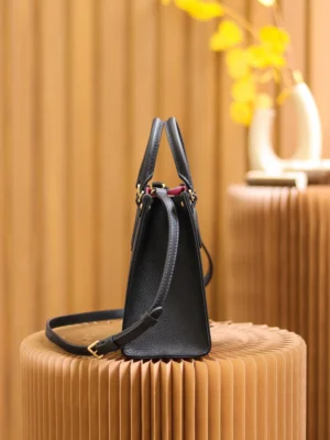 Onthego PM Bicolor Monogram Empreinte Leather Bag in black and beige, showcasing a stylish and compact design, set against a textured background.