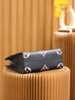 Replica Louis Vuitton OnTheGo PM Bicolor Monogram Empreinte Leather Bag in black and beige, displayed on a textured pedestal, showcasing its iconic design and luxurious materials.