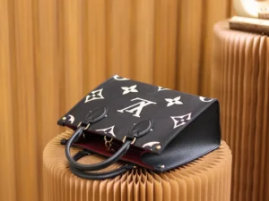 Onthego PM Bicolor Monogram Empreinte Leather Bag in black and beige, featuring iconic Louis Vuitton logo, displayed on textured surface, showcasing luxury design and compact style.