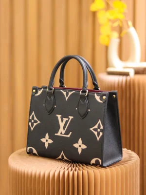 Louis Vuitton OnTheGo PM Bicolor Monogram Empreinte Leather Bag in black and beige, displayed on a textured pedestal with a warm background, emphasizing luxury and style.