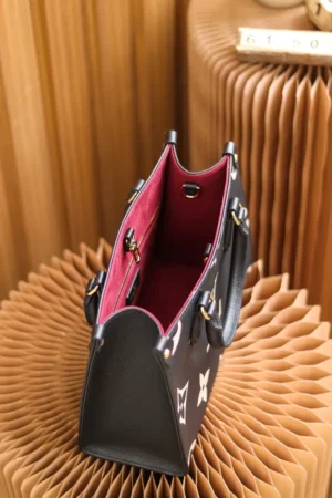 Onthego PM Bicolor Monogram Empreinte Leather Bag in black and beige, showcasing interior design with pink lining, displayed on textured background.