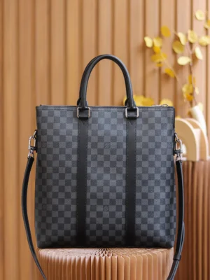 Montaigne BB Monogram canvas handbag in black checkered pattern, featuring dual handles and a detachable shoulder strap, set against a warm wooden backdrop.