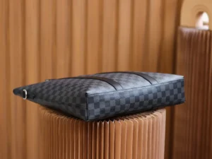 Montaigne BB Monogram canvas handbag resting on a textured pedestal, showcasing its sleek design and signature checkered pattern.