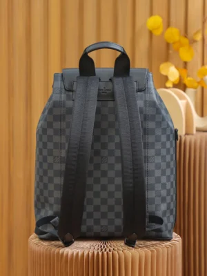 Discovery Backpack in Monogram Eclipse canvas, featuring a checkered pattern, adjustable black straps, and a sleek design, displayed against a wooden backdrop.