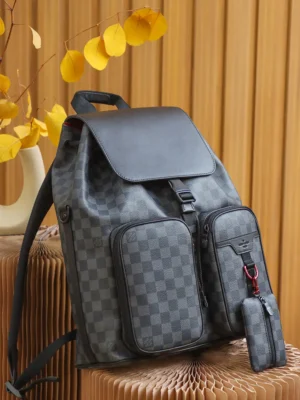 Discovery Backpack in Monogram Eclipse canvas with dual front pockets and a small accessory pouch, set against a textured backdrop, highlighting its versatile design and luxury appeal.