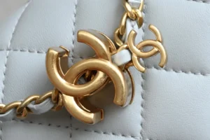 Chanel accessory gold tone metal chain and logo on white quilted leather background