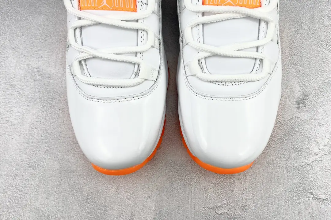 Nike Air Jordan 11 Retro 2022 white orange patent leather sneakers close-up on concrete background