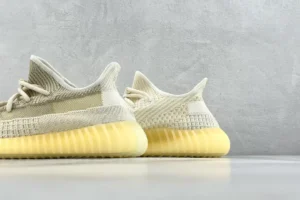 Adidas Yeezy Boost 350 V2 Natural shoes showcasing the light beige upper and distinctive yellow midsole, highlighting the sneaker's unique design and quality craftsmanship.