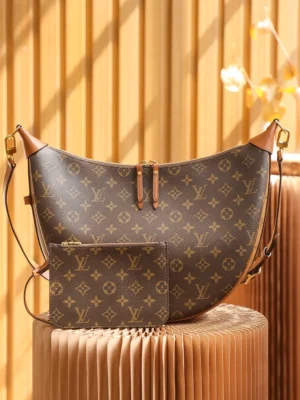 Montaigne BB Monogram canvas handbag featuring a crescent shape, brown canvas with Louis Vuitton monogram, and leather accents, displayed on a textured surface.