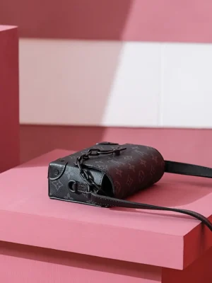 Steamer Wearable Wallet in Monogram Eclipse canvas on pink display, showcasing luxury design and versatility for men and women.