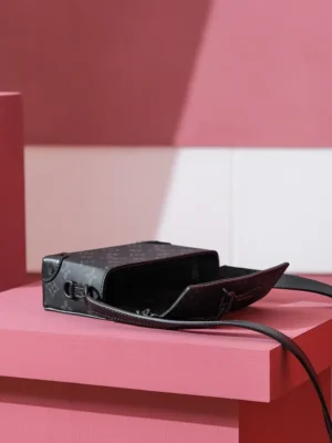 Steamer Wearable Wallet in Monogram Eclipse canvas displayed on a pink pedestal, showcasing its sleek design and versatile style for both men and women.