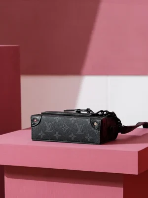 Steamer Wearable Wallet in Monogram Eclipse canvas positioned on a pink display, showcasing its sleek design and Louis Vuitton branding.