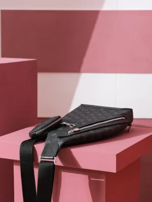 Duo Slingbag Taigarama in Monogram and Taiga leather on pink pedestal, showcasing stylish design and functionality.