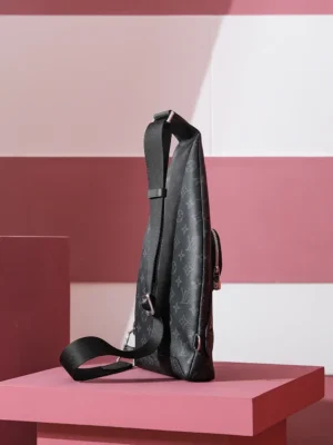 Duo Slingbag Taigarama in Monogram and Taiga leather displayed on a pink pedestal, showcasing its sleek profile and adjustable strap.