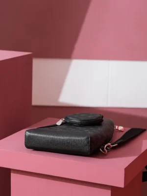 Duo Slingbag Taigarama in Monogram and Taiga leather displayed on a pink pedestal, showcasing its sleek design and compact shape.