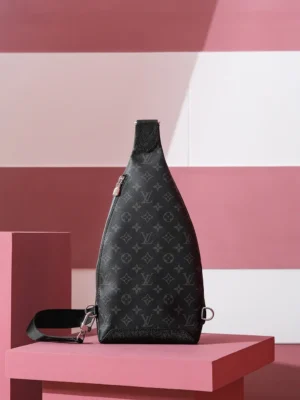 Duo Slingbag Taigarama in Monogram and Taiga leather, displayed on a pink geometric pedestal, showcasing a sleek design and luxury branding.