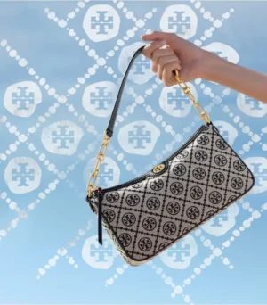 Hand holding Tory Burch Old Flower Series underarm bag replica with woven jacquard fabric and gold chain, against a patterned blue background.