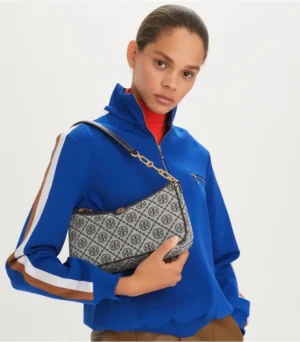 Model showcasing Tory Burch Old Flower Series underarm bag in woven jacquard fabric, wearing a blue zip-up jacket, with adjustable strap for versatile carrying options.