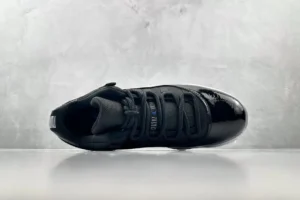 Black Jordan Air Jordan 1 sneaker featuring glossy patent leather and distinctive lacing design, showcased against a minimalist gray background.