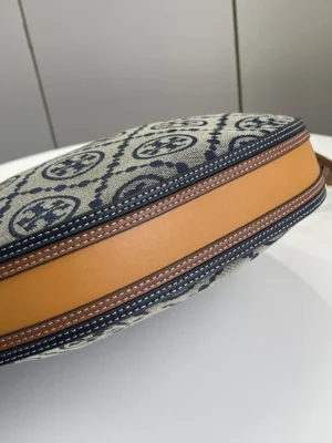 Tory Burch Monogram crescent bag replica showcasing woven jacquard fabric, featuring iconic TMonogram pattern and leather trim, emphasizing craftsmanship and design details.