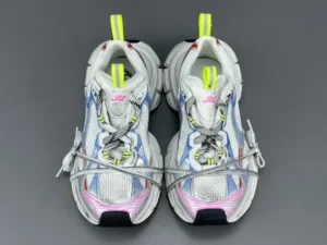 Balenciaga 3XL Mesh sneakers in gray and white with neon yellow accents, featuring a unique design and lace-up closure, displayed on a gray background.