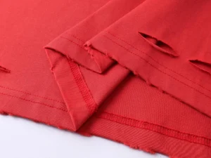Repsgoat Torn red cotton fabric with raw hem and distressed cutout details for clothing design