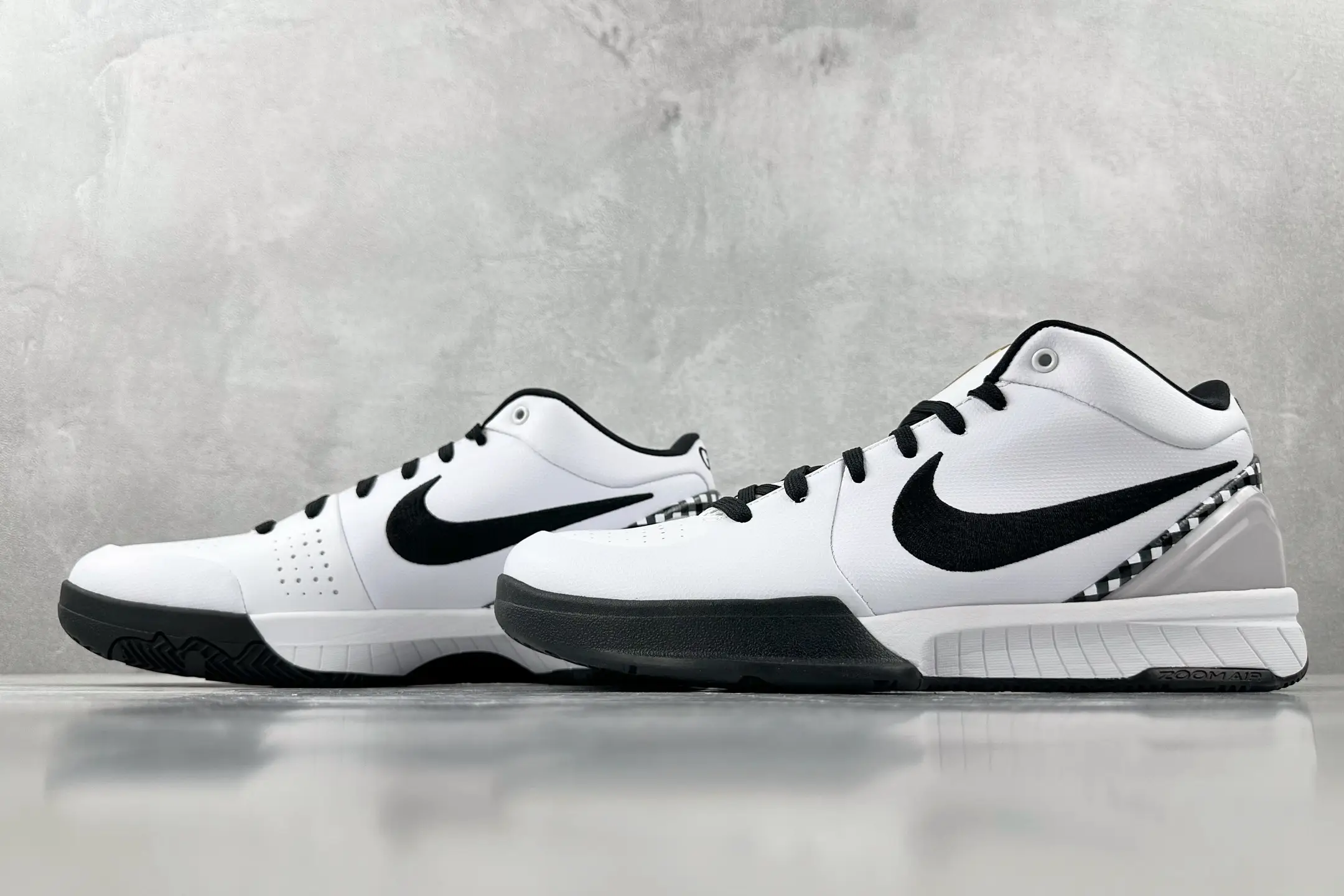 Nike Zoom Kobe 4 "Mambacita" G shoes in white and black colorway, featuring signature Nike swoosh and sleek design, displayed on a reflective surface.