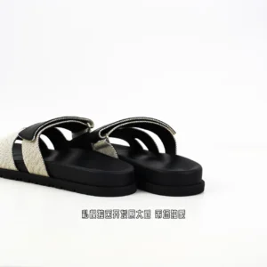 Hermes Aima slippers in black and beige, showcasing luxury design and premium materials, featured on an e-commerce page for high-quality replica shoes.