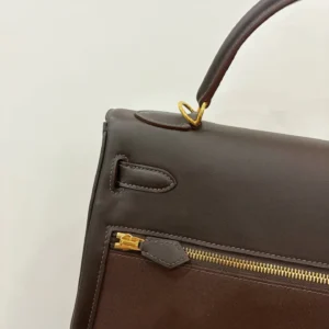 Hermes Kelly Lakis 28 bag in ebony leather with gold hardware detailing, showcasing the zipper and handle design.