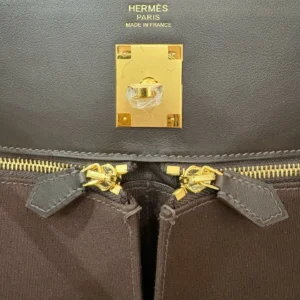 Hermes Kelly Lakis 28 bag in ebony leather featuring gold hardware, zipper closures, and embossed logo detail, showcasing luxury craftsmanship.