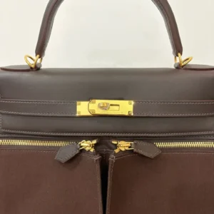 Hermes Kelly Lakis 28 bag in ebony and gold, featuring a structured design, gold hardware, and dual zipper closure, showcased for luxury replica apparel and accessories.