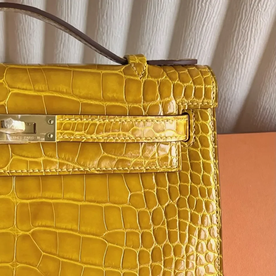 Hermès Kelly 25 yellow crocodile leather handbag with gold hardware and top handle close-up detail