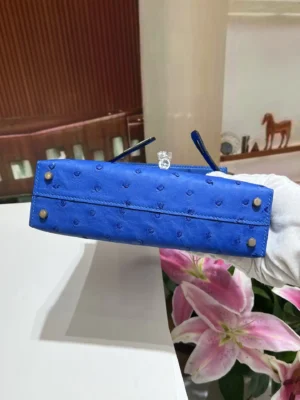 Herm&egrave;s Kelly 25 blue ostrich leather bag gold hardware bottom view with pink lilies in background