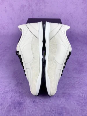 Chanel 25P series casual sports shoes in pure white, showcasing sleek design and craftsmanship, displayed against a purple background.