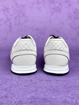 Chanel 25P series casual sports shoes in pure white, featuring a quilted design and sleek silhouette, displayed against a purple background.