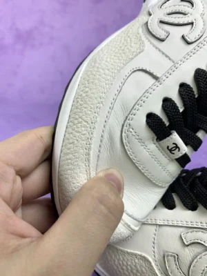Chanel 25P series casual sports shoes in pure white, featuring textured leather and black laces, showcasing craftsmanship and luxury design.