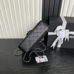 Black Chanel 25B Exquisite Double C-Button CF Series AS5 bag with a silver chain, displayed beside a gift box adorned with a white flower, highlighting its luxurious design and craftsmanship.