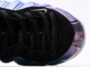 Nike Air Foamposite One NRG sneaker close-up, featuring a black upper with galaxy-themed design and laces, emphasizing its premium quality and unique style.