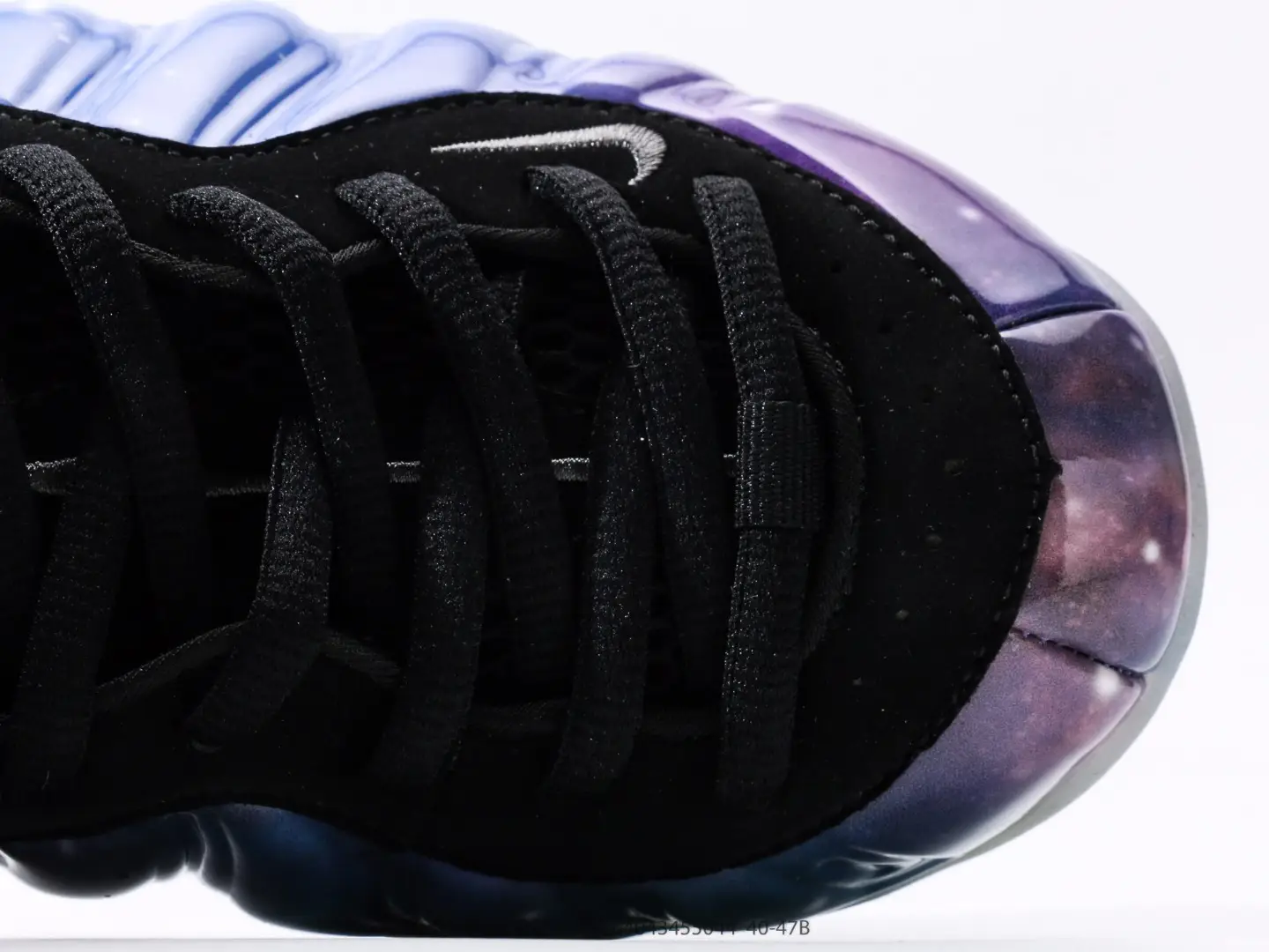 Nike Air Foamposite One NRG sneaker close-up, featuring black upper with purple galaxy pattern and silver logo, highlighting unique design elements for sneaker enthusiasts.