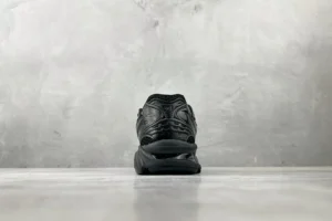 ASICS Gel-Coffee 14 sneaker viewed from the back, showcasing its sleek black design and textured upper against a minimalist gray background.