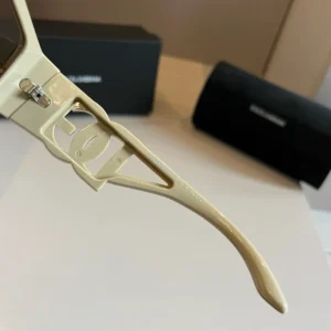 Close-up of Dolce&Gabbana sunscreen sunglasses showing the arm detail and logo, with a black protective case in the background, highlighting luxury fashion accessories.