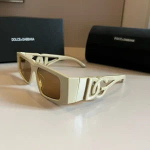 Dolce&Gabbana sunscreen sunglasses with a stylish design and logo, displayed on a neutral background alongside branded packaging.