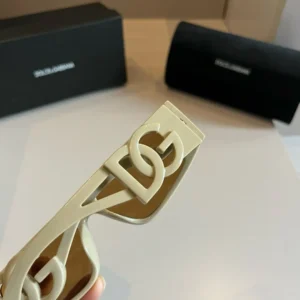 Dolce & Gabbana sunglasses showcasing the distinctive D&G logo on the frame, with branded packaging in the background.