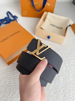 Louis Vuitton men's replica belt featuring a gold letter buckle, held in hand, with branded packaging in the background.