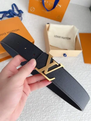 Hand holding a Louis Vuitton replica belt with a gold letter buckle, displayed alongside branded packaging, emphasizing luxury fashion accessories.